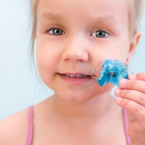 Dental plate. Expansion of the jaw in a child. A plate to heaven. There is not enough room for the molars. Happy girl holding an orthodontic plate in her hands
